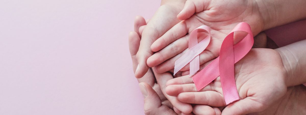 hands holding pink ribbons on pink background, Breast cancer awareness and October Pink day