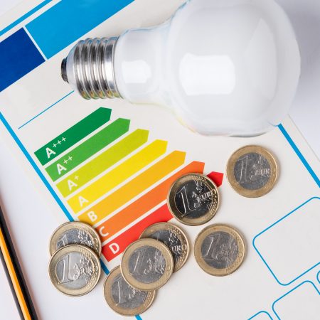Energy efficiency scale with a light bulb, a pencil to make calculations and coins representing the cost of energy